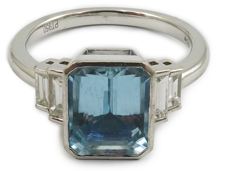 An Art Deco style platinum and single stone emerald cut aquamarine set dress ring, with four stone graduated baguette cut diamond set shoulders